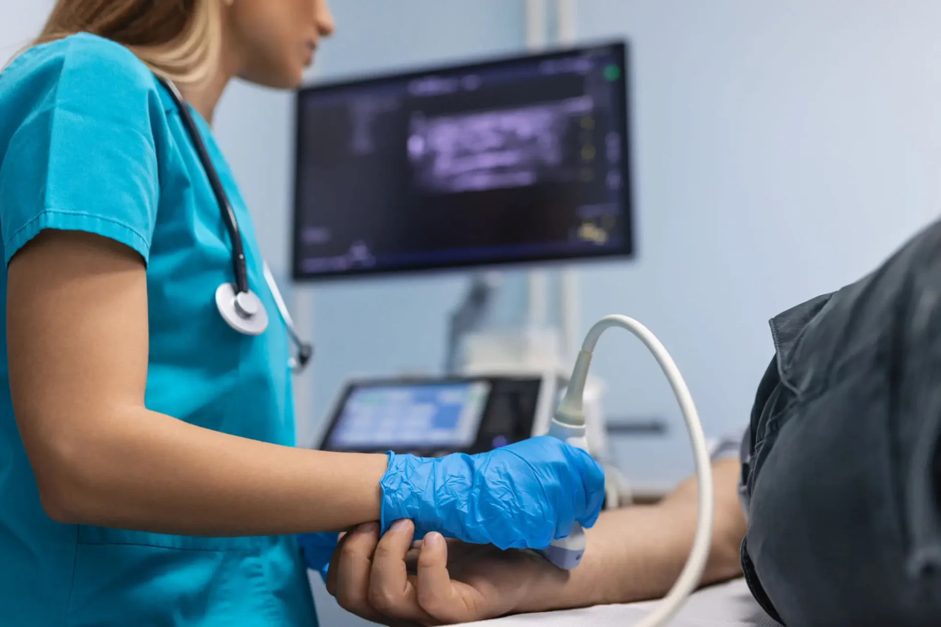 Nurse performing ultrasound on patient's arm.