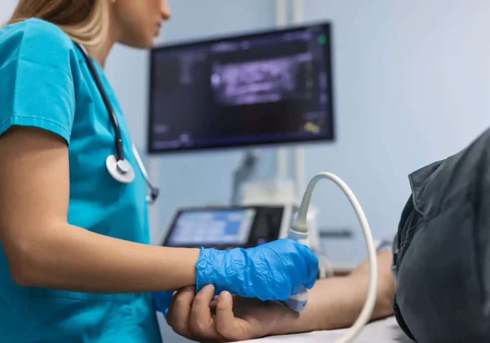 Nurse performing ultrasound on patient's arm.